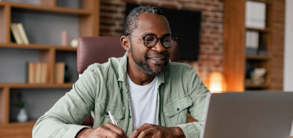 Smiling Middle Aged African American Male in Glasses on Laptop