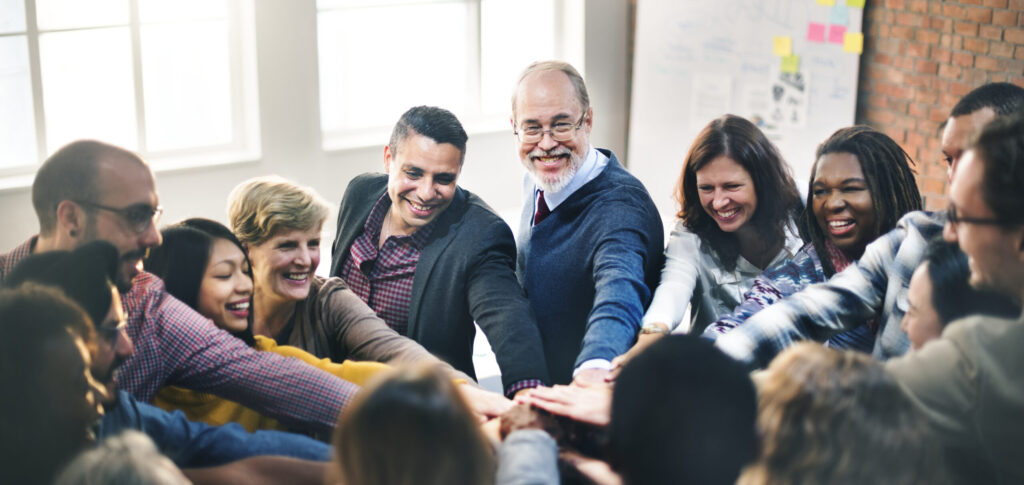 Diverse group of people in a circle putting their hands together in the center