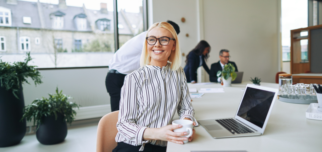 Businesswoman Smiling and Drinking Coffee in an Office